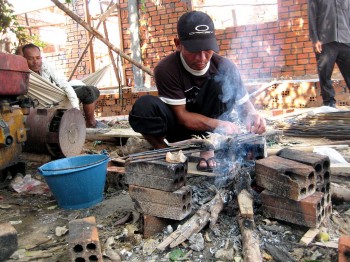 Einer der Arbeiter grillt Fisch