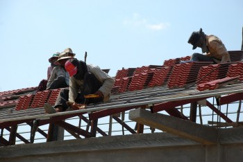 Arbeiter verlegen Ziegel am Dachstuhl